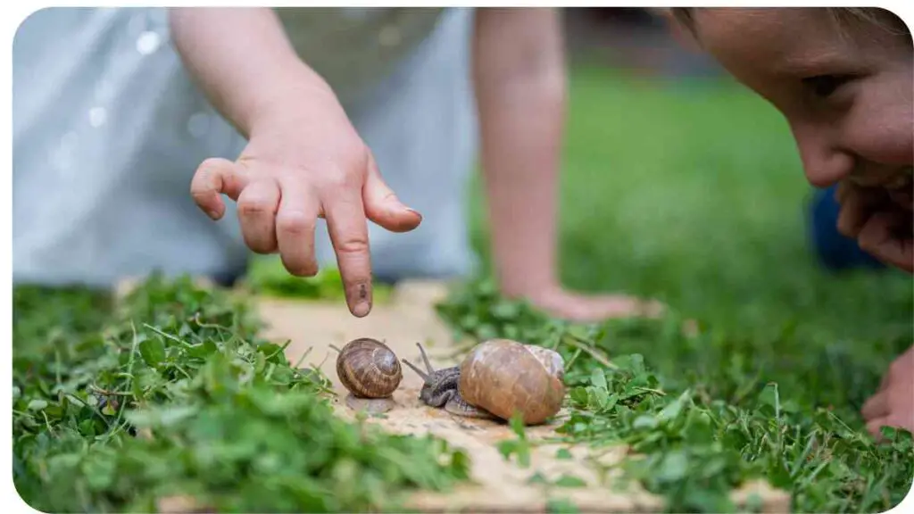 two children playing with snails in the grass