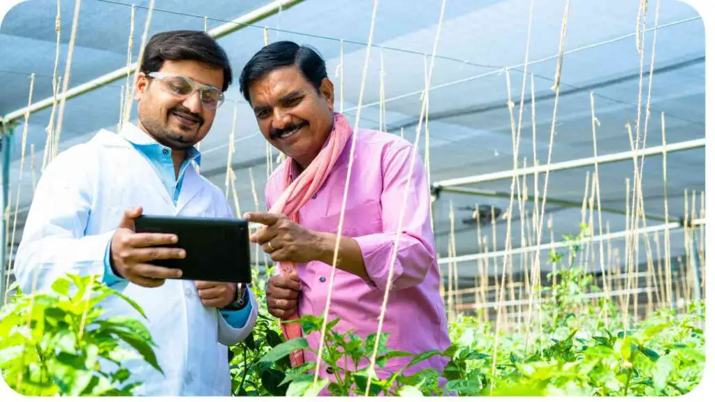 two people standing in a greenhouse looking at a tablet