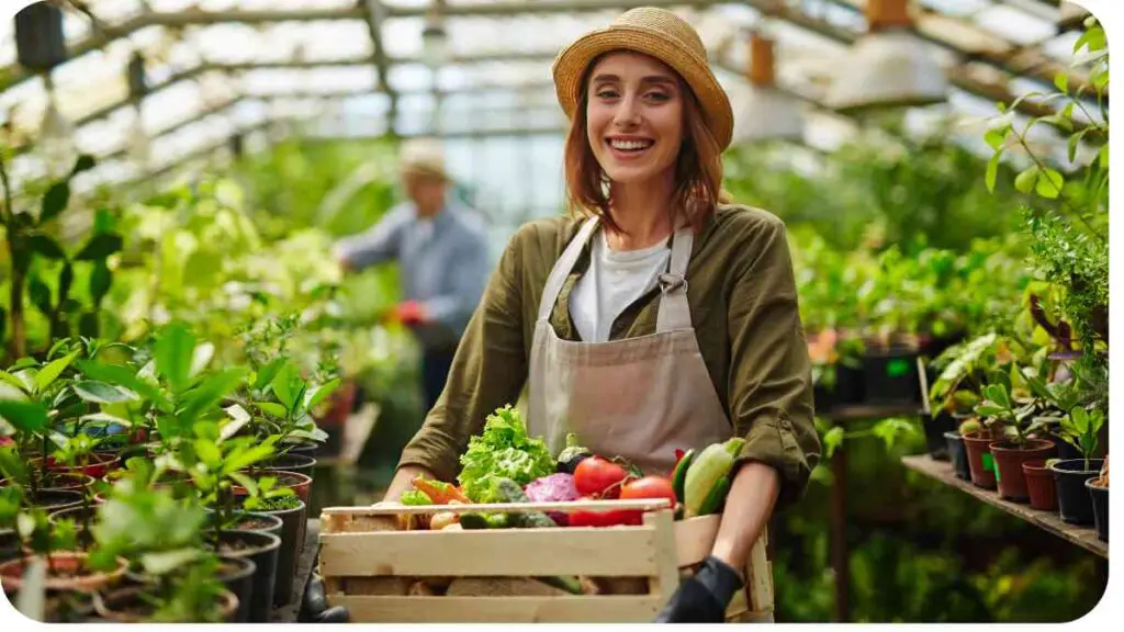 a person holding a crate of vegetables in a greenhouse