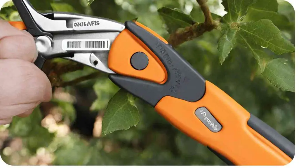 a close up of a hand holding an orange and black pruning shears