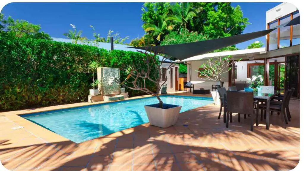 an outdoor pool and patio area with chairs and umbrellas