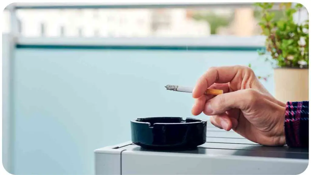 a person holding a cigarette in front of a black ashtray